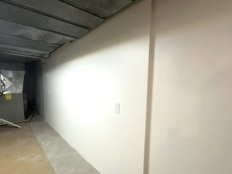 Finished basement wall sanded flat and painted, with no visible seams under raking light