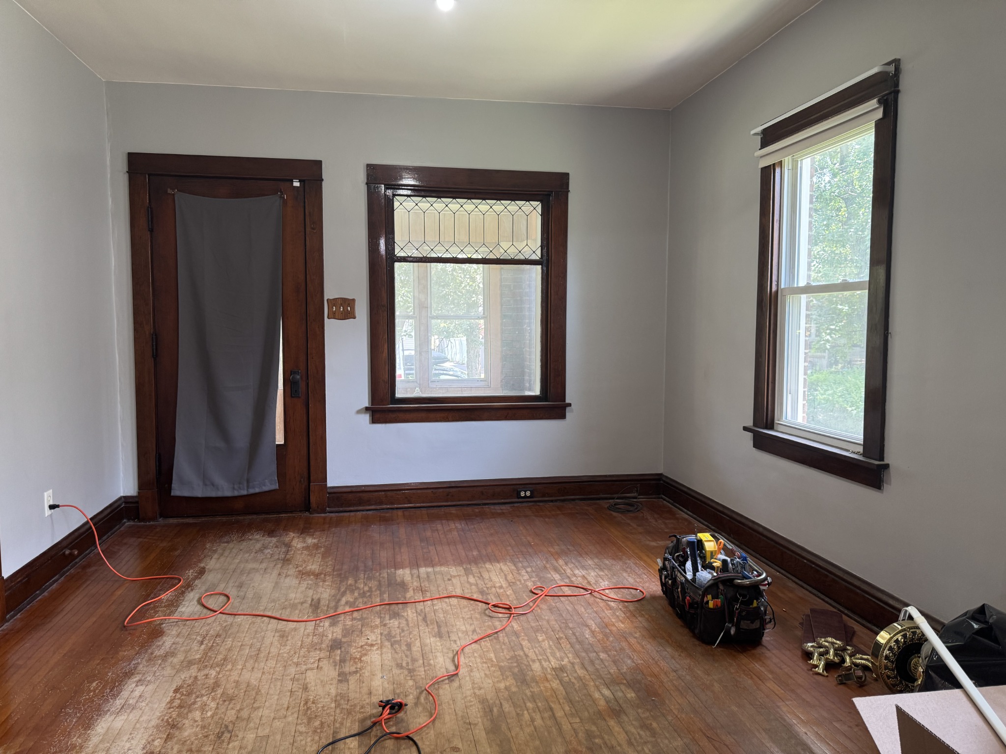 Living room before painting with gray walls and dark wood window trim