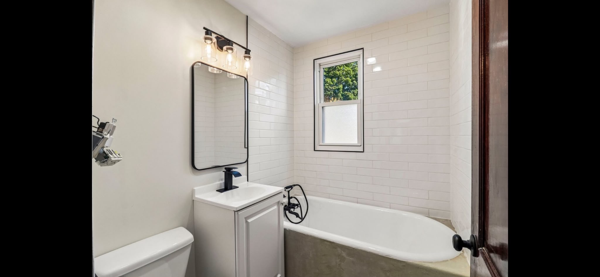 White subway tile, a white vanity and contrasting black accents in the latest project photo. Bathroom remodeling project in Joliet, Illinois.