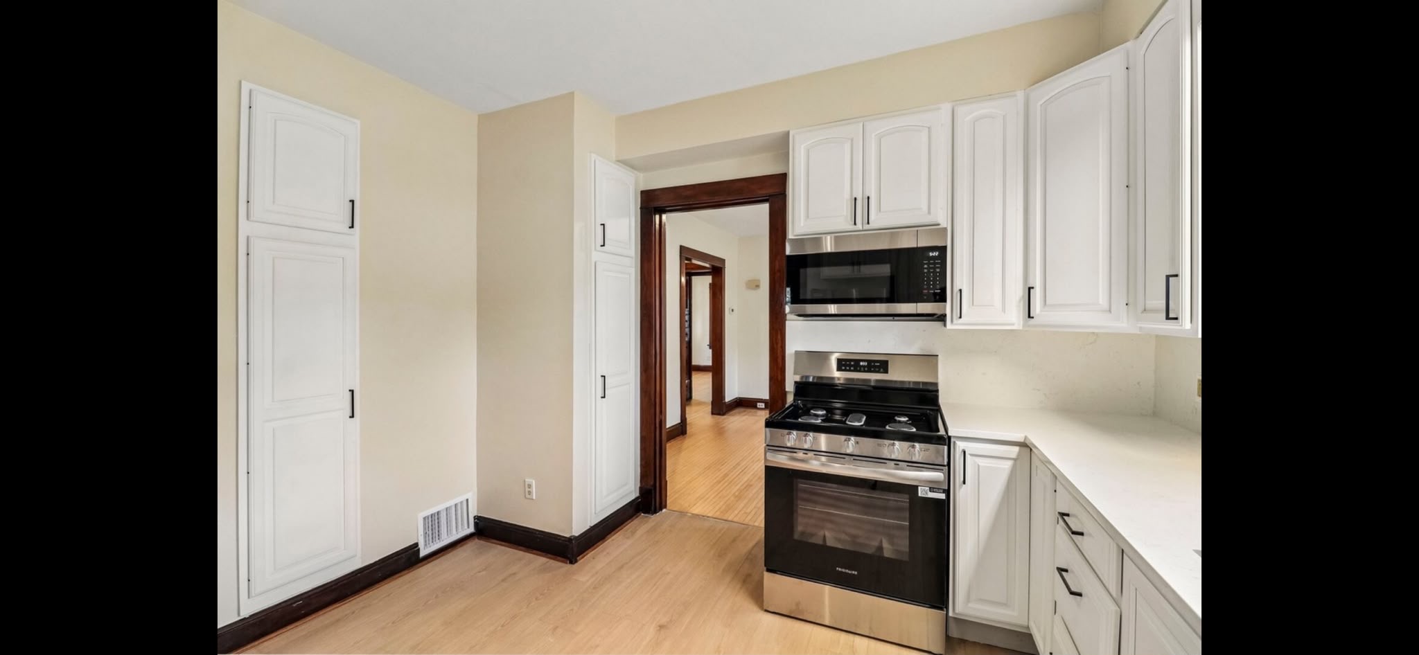A second view of the painted cabinets and light wood-look vinyl flooring. Kitchen remodeling in Joliet, Illinois.