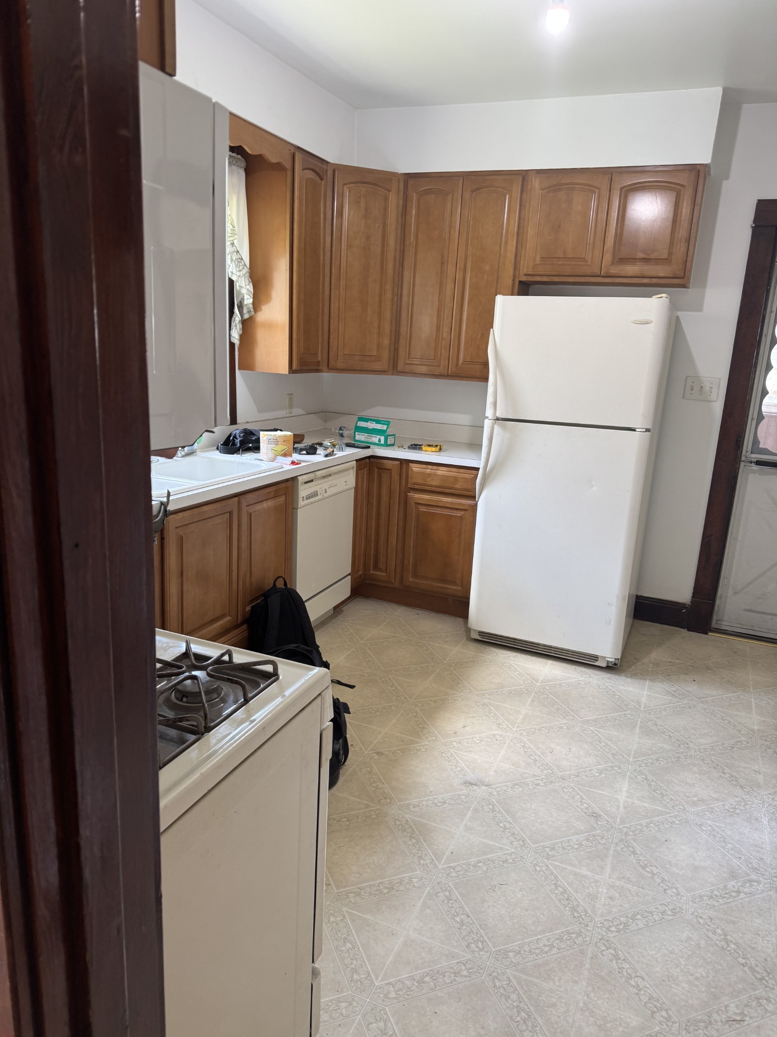 The kitchen before the refresh, with wood-finish cabinets and the original patterned floor. Kitchen remodeling in Joliet, Illinois.