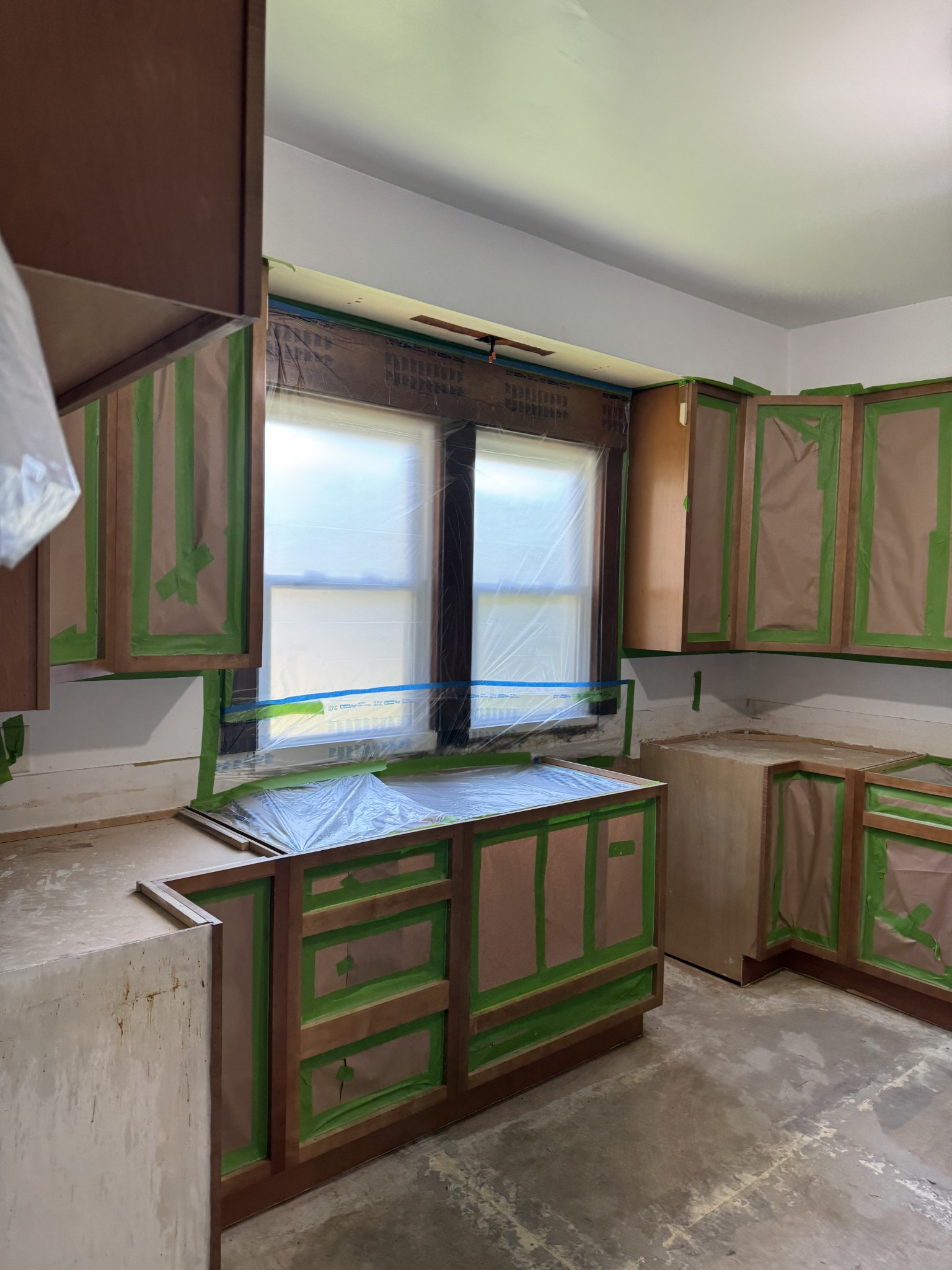 Cabinet openings and windows masked off during preparation for painting. Kitchen remodeling in Joliet, Illinois.