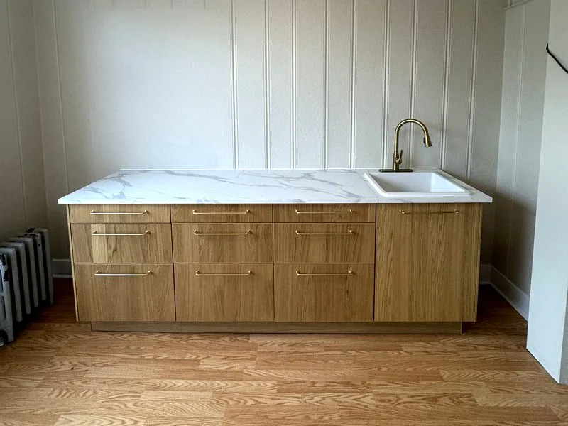 Completed kitchen with oak cabinets, light countertops and brass hardware