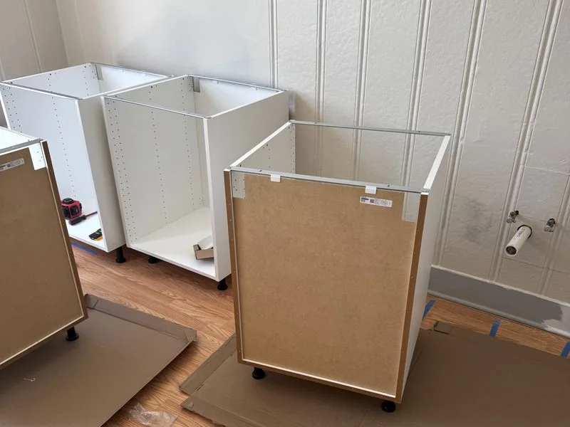 Kitchen cabinet boxes assembled and leveled on adjustable feet during installation in a Wilmette home