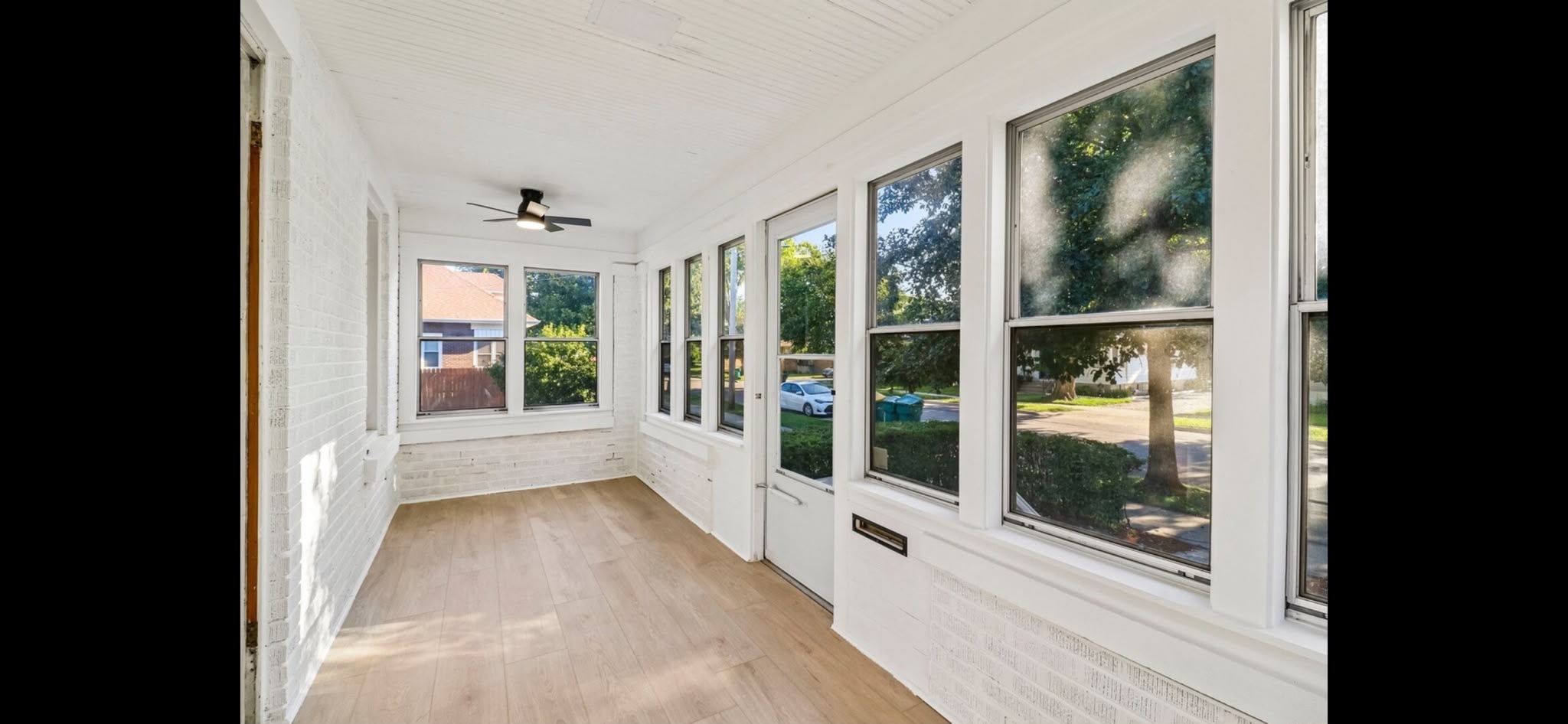 Sunroom in Joliet after remodeling with white painted brick, white trim and light flooring